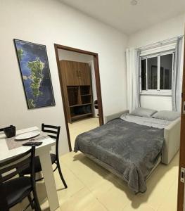a bedroom with a bed and a table and a desk at Cantinho do Mané in Florianópolis