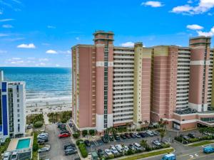 un grand bâtiment rose avec l'océan en arrière-plan dans l'établissement Beautifully Renovated Oceanfront 2 BR Condo with Oversized Balcony! Bay Watch 509, à Myrtle Beach