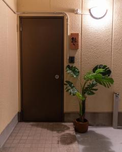 uma porta preta num quarto com uma planta em 大吉屋本館 ワンフロア貸切部屋 名駅離れ em Nagoya