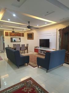a living room with couches and a flat screen tv at Elly Homestay Shah Alam in Shah Alam