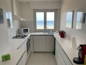 a white kitchen with a sink and a microwave at Belle vue - Vue panoramique sur la Mer in Cabourg