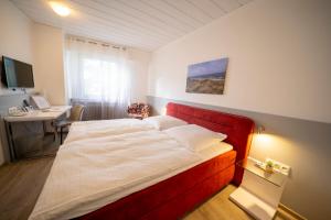 a bedroom with a bed with a red headboard and a desk at Mühlenkamp Hotel & Gastronomie in Oelde