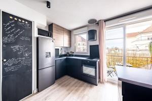 a kitchen with a black refrigerator and a large window at Appartement Proche Disney Paris Vidéo-Projecteur in Bussy-Saint-Georges