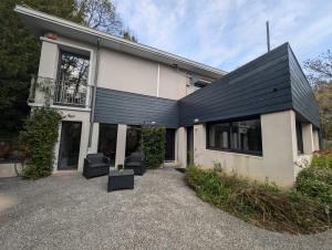 a house with a black roof and chairs in front of it at B&B Le Gorget in La Tronche