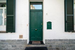 a green door on a white building with green shutters at Villa Verde - 300m From Sea in Bordighera