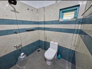 a bathroom with a toilet and a window at Blue Cove Villa Varkala in Varkala