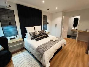a bedroom with a large bed with a black headboard at Bel-Air Guesthouse in Klerksdorp