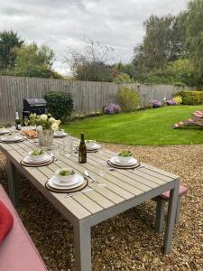 a picnic table with food and a bottle of wine at King Arthur's Rest House, Hot Tub & Garden Sleeps 10 in South Cadbury