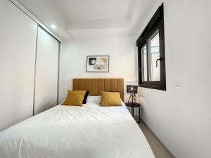Un dormitorio con una cama con sábanas blancas y almohadas amarillas. en Villa Hestia, en Alicante