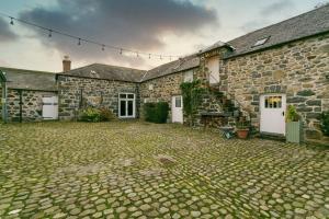 a stone building with white doors and a stone courtyard at Tal y Bont Barns in Bangor