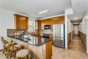 Una cocina con gabinetes de madera y un refrigerador de acero inoxidable. en Beach Club 2B - 201A by Premier Island Management Group, en Pensacola Beach