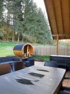 a wooden table with chairs and a wooden barrel at Chalet cosy & confort haut de gamme - Sauna, Spa, Clim in Anould