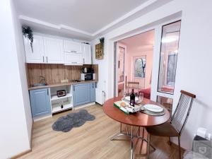 キシナウにあるRentHouse Apartments City Gates #5の木製のテーブルのあるキッチンと白いキャビネットのあるキッチン