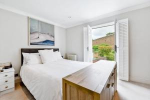 a white bedroom with a large bed and a window at Chic 3-Bed Townhouse,2 Mins to Windsor's Long Walk in Windsor