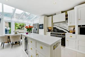 a kitchen with white cabinets and a large window at Chic 3-Bed Townhouse,2 Mins to Windsor's Long Walk in Windsor