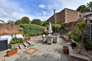 a patio with a table and chairs and an umbrella at Chic 3-Bed Townhouse,2 Mins to Windsor's Long Walk in Windsor