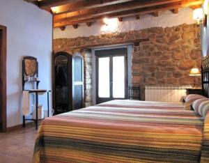 Un dormitorio con una cama grande con una pared de piedra. en Las Frascuelas, en Almajano