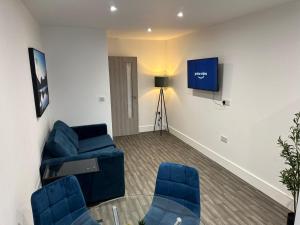 a living room with blue chairs and a tv at Modern Long Eaton Flat - Ideal for Work or Leisure in Long Eaton