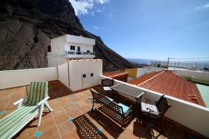 a balcony with chairs and a building with a mountain at Casa Emma in Valle Gran Rey
