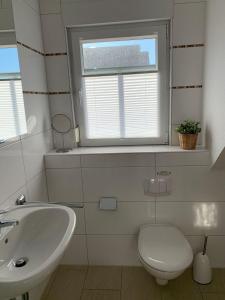 a bathroom with a sink and a toilet and a window at Haus-am-See-Kolkstr-1-OG-rechts in Norddeich