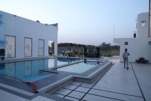 a man walking next to a swimming pool on a building at Royal Delight Resort in Madīna