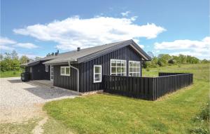 a black house with a fence in a field at Three-Bedroom Holiday Home In Grenaa in Grenå +20 photos