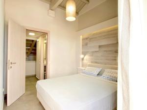 a bedroom with a white bed with a wooden headboard at Barbati Alpha MiniVilla by DadoVillas in Barbati +20 photos