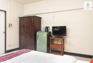 a room with a refrigerator and a tv and a bed at Sripoom House 1 in Chiang Mai