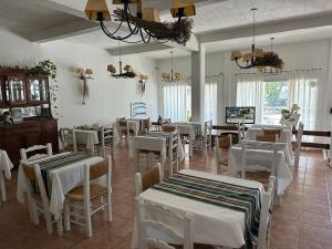 a dining room with white tables and chairs at La Posada de los Robles in Las Grutas