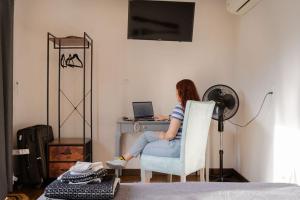a woman sitting in a chair at a desk with a laptop at CASA VALPARAISO Suites in Saltillo