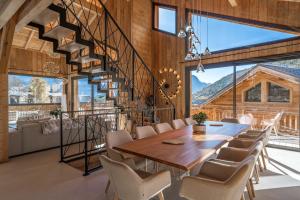 una sala da pranzo con tavolo, sedie e scala di Chalet JERI Spa Piscine Serre Chevalier a Briançon