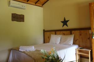 1 dormitorio con 1 cama con una estrella en la pared en Pousada Luar do Cipó, en Serra do Cipo