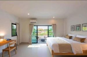 Un dormitorio con una cama y un escritorio y un balcón. en Modern House CNX, en Chiang Mai