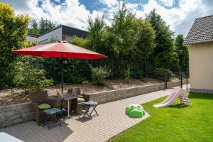 Un patio con una mesa y una sombrilla y un tobogán. en Wolke Siegen, en Siegen