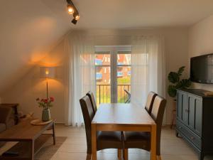a dining room with a table and a television at Haus-am-See-Kolktstr-1-OG-links in Norddeich +9 photos