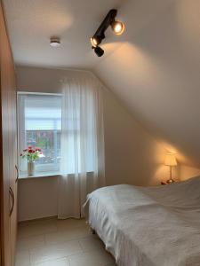 a bedroom with a ceiling fan and a window at Haus-am-See-Kolktstr-1-OG-links in Norddeich