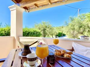a wooden table with two glasses of orange juice and pastries at Kostas Beach Estate with private pool by DadoVillas in Astrakeri