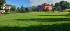 a large field of green grass with a house in the background at Ca'Nostra in Bagnolo Piemonte +9 photos