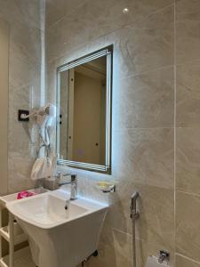 Un baño con un lavabo blanco y un espejo. en شقق طلال الفندقية, en Al Ula