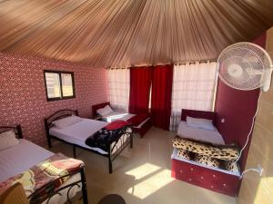 a room with three beds and a fan at Wadi Rum Authentic Camp in Wadi Rum