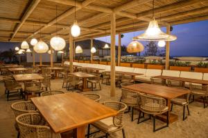 ein Restaurant mit Holztischen und Stühlen und Lichtern in der Unterkunft Yemanjá Hotel by Preabeach Experience in Prea