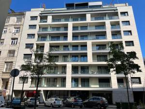 a large white building with cars parked in front of it at River Living Apartman in Budapest