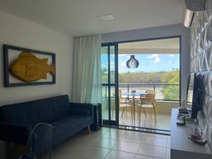a living room with a blue couch and a balcony at Apto 304-D, 1 quarto completo! in Tamandaré