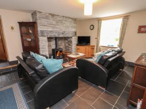 a living room with two leather chairs and a stone fireplace at Ty Siabod in Betws-y-coed