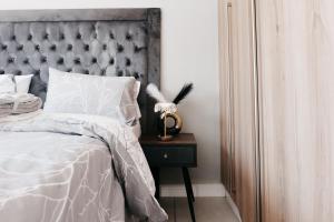a bed with a gray headboard and a nightstand with a side table at Exquisite Getaway - Luxury Apartment in Sandown +17 photos
