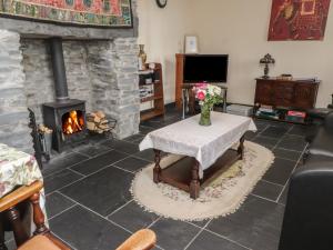 a living room with a fireplace and a table with flowers at Ty Llugwy in Betws-y-coed