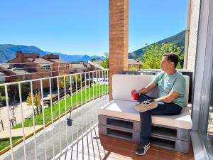 a man sitting on a bench on a balcony at Apartamento rural en el Berguedà "Lluis & Antonia" A Ac in Sant Jordi de Cercs