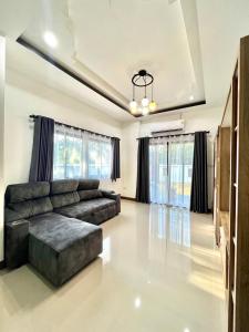 Una sala de estar con un sofá y algunas ventanas. en Just Home Hua Hin, en Ban Huai Sai Tai