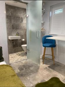 baño con ducha, aseo y silla azul en Oakwood Cabin Retreat in Bexleyheath, en Kent