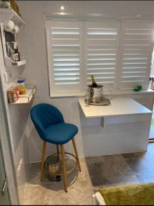 Una cocina con un taburete azul y una encimera blanca. en Oakwood Cabin Retreat in Bexleyheath, en Kent